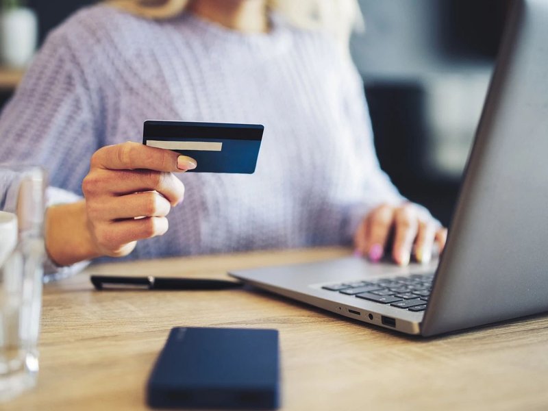 Woman Holding A Credit Card While Looking At Her Laptop